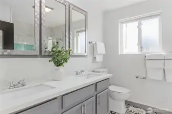 Hall bath with double quartz vanity sinks, and ornate ceramic tile floor.