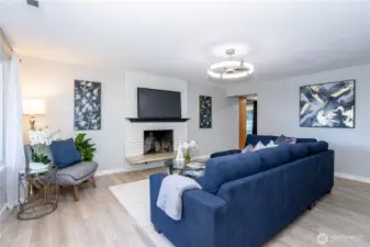 From this angle, the scale of the living room really stands out. The sectional placement highlights how much seating the space can handle without feeling crowded. The fireplace and mounted TV wall create a natural media hub, perfect for movie nights or game days. Updated lighting overhead adds a contemporary touch while keeping the room well illuminated in the evenings. The flow toward the adjacent spaces feels seamless, reinforcing the open yet defined layout.