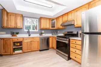 From this perspective, you get a clear look at the kitchen’s working side. Stainless appliances, generous counter space and plenty of cabinetry make meal prep practical and efficient. The lighting overhead keeps the space bright, while the window over the sink adds natural light and a view out to the yard — a small detail that makes daily routines more enjoyable.