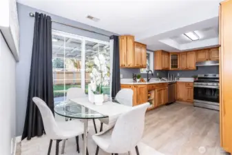 This angle shows how the kitchen flows directly into the dining nook, creating a casual eat-in setup that works well for daily meals. The glass table staging demonstrates there’s comfortable room for seating without crowding the space. The sliding door nearby enhances indoor-outdoor connectivity and keeps the dining area light and airy.