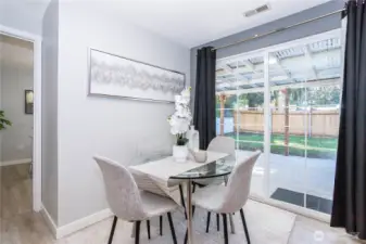Here you see the dining space’s connection to the backyard more clearly. Large glass sliders bring in natural light and offer easy access to outdoor entertaining or play space. Curtains frame the doors nicely, softening the look while maintaining privacy when needed. It’s a bright, practical extension of the kitchen.