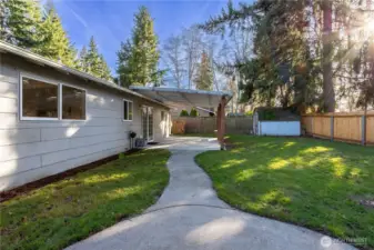 This view highlights the yard’s layout, showing the curved walkway that guides you through the outdoor space. The lawn offers usable green space for play, pets or gardening, while fencing provides privacy and security. Mature trees add a natural backdrop and seasonal beauty. The setting feels peaceful and usable rather than overly landscaped or high maintenance.