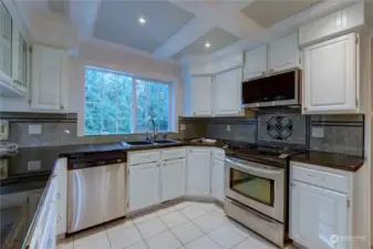 Notice the beamed ceiling, all white cabinets, black tile countertops and stainless steel appliances in the kitchen