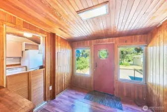 Porthole from a ship in the front door. Kitchen pass through from the entry. Warm wood paneling throughout.