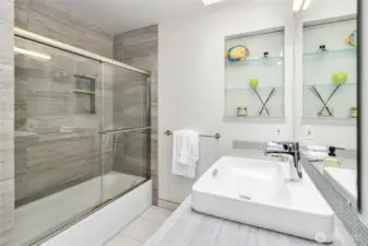 The second-floor bath features a vanity, shower, and tub, offering both style and functionality.