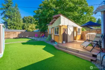 Here you can see a full view of the backyard including the firepit gathering area, the beautiful expanse of artificial grass, the deck, and the outdoor room.