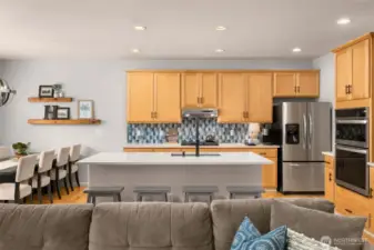 Updated kitchen includes quartz counters, stainless appliances, counter seating and warm wood cabinets.