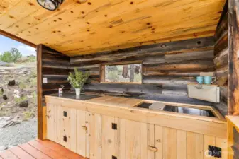 Beautiful outdoor kitchen with reclaimed wood from an old home (circa 1912) that was taken down on the property. The opening on the back wall is a "hatch door" which can be open or closed. Sink with running water (small holding tank), Italian porcelain tile and cedar countertops. Cabinets feature plenty of storage.