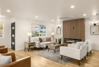 Spacious open-concept living area featuring a cozy wood slatted fireplace and large windows for a bright, airy feel