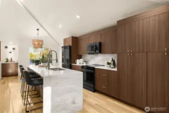 The kitchen presents a statment kitchen island with a waterfall finish. Made of durable, stain & water resistant thick 3cm quartz slab