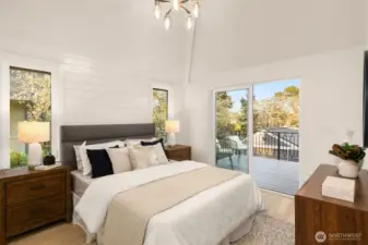 The primary suite is open and airy, offering access to the new deck