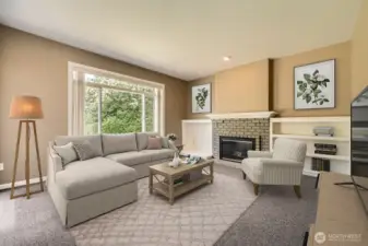 The family room is spacious with large windows bringing in plenty of natural light. It features built-in shelving, a brick gas fireplace, and more.