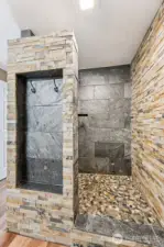 Stunning natural stone-accented walk-in shower with a built-in nook with hooks to hold your towel or robe. Even better in person.