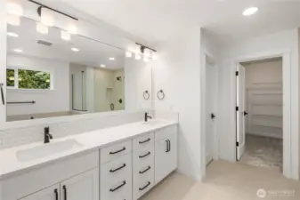 This spacious ensuite bath features an extended double vanity with quartz countertops, black fixtures, and abundant drawer storage. Soft lighting and a full-width mirror create a bright, calm start-to-finish routine, with direct access to the walk-in closet for everyday convenience.    These photos are from lot 3 at Gooden Hollow, the actual home for sale. However, other homes may vary, so all photos, renderings, site maps, and floorplans are for visualization purposes only. Plans, colors, building orientation, finishes, home outlook, and other details can and WILL vary.