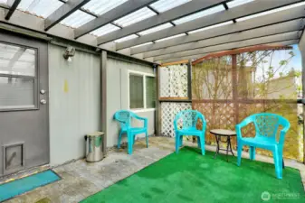 The covered  back porch looking North. There are plants and trees that provide shade and privacy during the summer.
