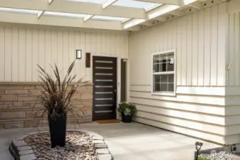 Lovely covered entry featuring a landscaping island and gorgeous solid wood mid-century 5 lite door. You'll never get rained on here!