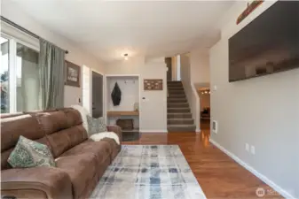 Living room looking to carpeted stairs that lead to the upper level, and beyond you will notice the lower level family room. Note the tile floor entry and the darling nook with a large shelf & shiplap surround.