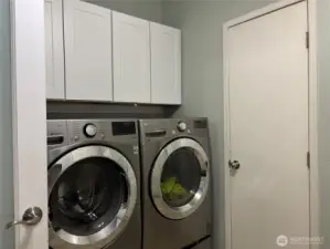 closer look at the washer and dryer as they stay with the home, plus cabinets above for storage.