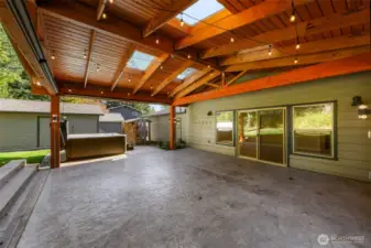 GRAND chalet style covered patio with stained concrete, skylights and powered lights and plugs next to the large hot tub