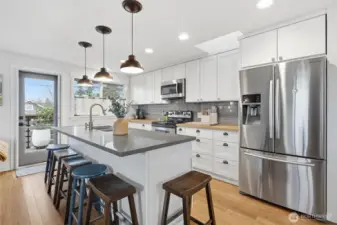 The updated kitchen features bar seating, stainless appliances, quart and butcher block counters.