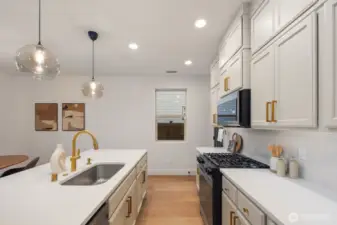 Functional kitchen workspace with generous counter space, upper cabinetry for storage, and modern appliances positioned for efficient everyday cooking. The layout keeps prep areas organized while maintaining sightlines to the rest of the main living space.