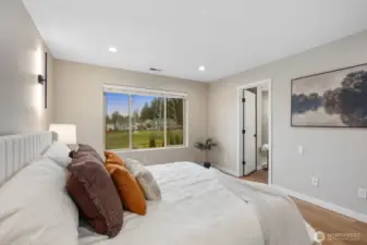 From this angle, the primary suite highlights its airy proportions and calming neutral palette. Large windows bring in natural light and neighborhood views, enhancing the serene atmosphere of this private bedroom retreat.