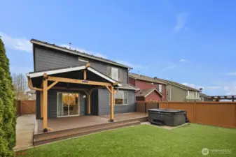 Full view of the backyard highlighting the large covered deck, private fencing, and neatly maintained yard space. The layout offers room for outdoor seating, entertaining, and everyday enjoyment just steps from the home.