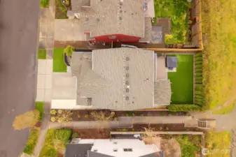 Straight-down aerial perspective showing the home’s roofline, driveway access, backyard deck structure, and fenced yard. This angle provides a clear view of the property layout within the neighborhood.