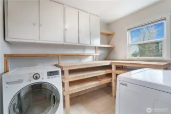 A spacious utility room includes a washer and dryer, along with plenty of cabinets and shelving.