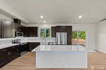 Note the under cabinet lighting, Stainless steel appliances, and barstool seating area.