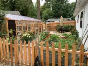 The fenced side yard offers a greenhouse and plenty of raised garden beds, providing the perfect space for your gardening enjoyment.