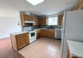 The light filled kitchen has white quartz counter tops and a lot of cupboard space. It is open to the dining room.