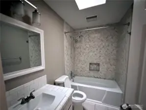 Stylish second bathroom with bath tub and skylight