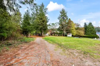 Driveway into the property from the shared drive.  The little structure in the orchard is the shared 3 party well - in great condition.