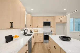 The open floor plan leads directly into a bright kitchen, anchored by light wood cabinetry and crisp quartz countertops.