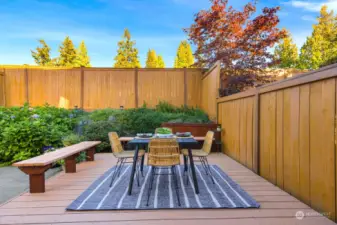 Elevate your outdoor experience with a dedicated dining area, set against a backdrop of lush greenery and privacy fencing.