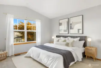 A serene retreat awaits you in this primary bedroom, featuring large windows that invite natural light and views of the vibrant trees outside.