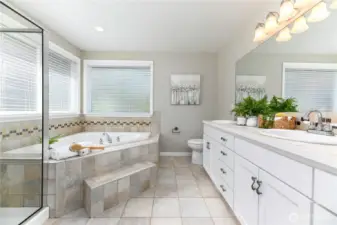 The spa-inspired bath offers a tranquil retreat, featuring a jetted soaking tub, a spacious walk-in shower, dual vanities, and high-end finishes, creating a serene, luxurious experience.