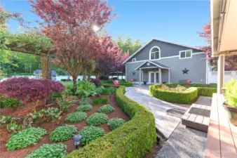A beautifully stamped concrete walkway leads to the perfect shop, complete with guest quarters, offering both functionality and a private retreat for visitors.