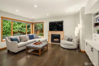 White Oak hardwood floors flow throughout the main level into a spacious family room with one of two fireplaces with travertine tile surround, built-in bookcases, cabinets and views to the outdoor space.