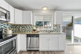Kitchen window and slider door allows light to pour into the open kitchen and dining nook.