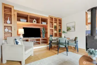 Main home living room with hardwood floors, woodstove, western views of the ship canal, and custom built in entertainment center.