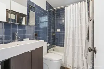 Main floor remodeled bathroom with stone tile floors and tiled walls and shower.