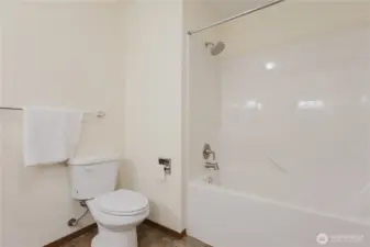 Primary en-suite 5 item bathroom: two sinks, toilet, bathtub with shower