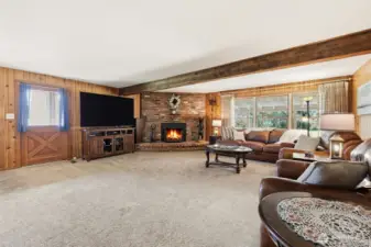 Spacious livingroom with a woodburning fireplace. Door leads out to the very large covered porch.