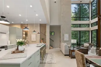 Here is a view of the kitchen open to the living space and there is a 2nd story door to the wrap around deck on the south side of the home as well as on the north side. View of stairs going up to the primary bedroom.