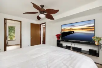 Primary bedroom features ceiling fan, view overlooking private and serene backyard, and a spacious walk-in closet.