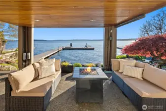 Covered outdoor living space offers the perfect spot to gather around the fire pit, listen to the waves, and enjoy shoreline views—day or night.
