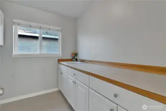 Laundry room, which is on the second floor, where all the bedrooms are located. It has ample cabinet storage and a counter with a sink.