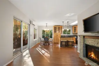 Living room toward dining and kitchen, with large slider to private deck overlooking wooded wonderland.  Photo taken from just inside entry door.  Electric fireplace on right.